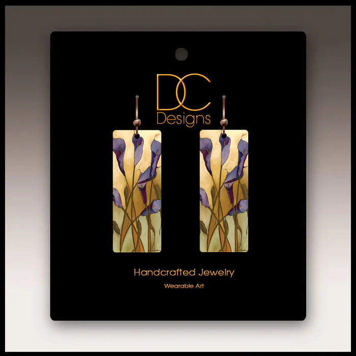 Pair of earrings on a black card with 'DC Designs' branding