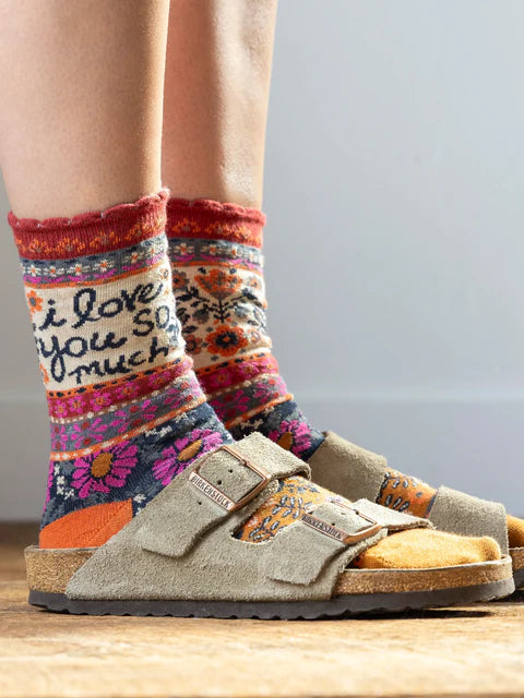 Colorful patterned socks with text worn with brown sandals on a light background