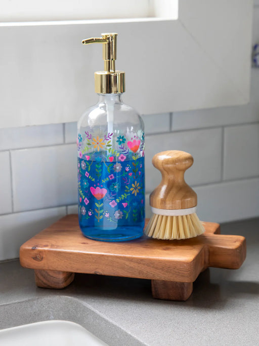 Decorative soap dispenser with floral design on a wooden soap dish in a kitchen setting.