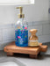 Decorative soap dispenser with floral design on a wooden soap dish in a kitchen setting.