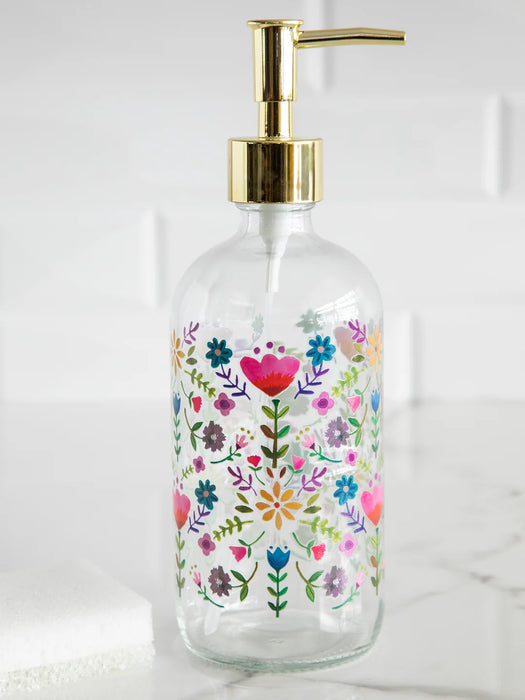 Glass soap dispenser with floral design and gold pump on a white background