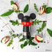 Pepper grinder with Mickey Mouse design surrounded by food and greens on a light surface