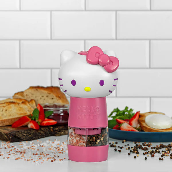 Pink Hello Kitty-themed pepper grinder on a kitchen counter with food in the background.