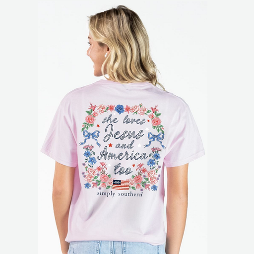 Woman wearing a pink t-shirt with floral and text design, standing against a white background.