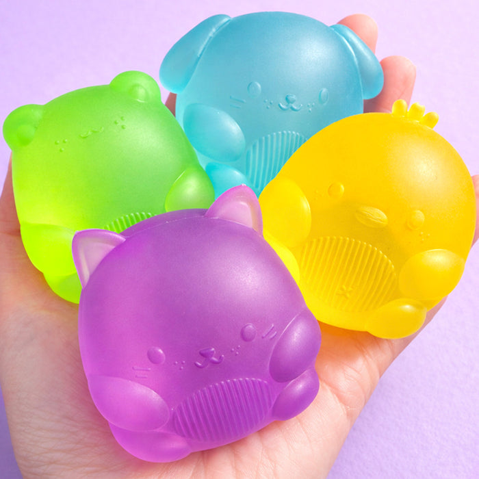 Four colorful silicone sanding blocks shaped like animals held in a hand against a light purple background.