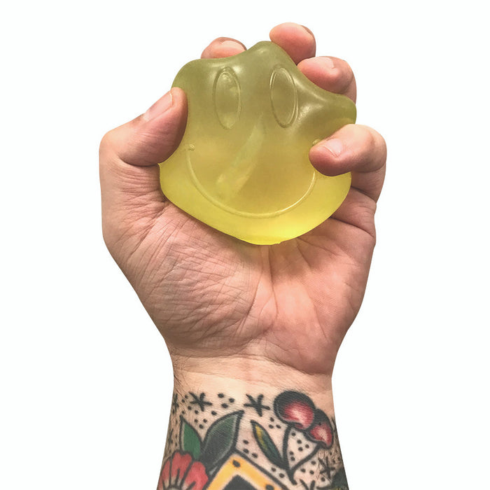 Hand holding a yellow rubber duck shaped like a paw print against a white background