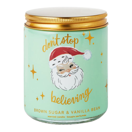 Candle jar with Santa Claus illustration and text 'don't stop believing' on a light green background.
