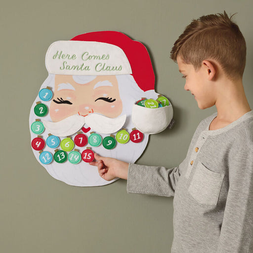 Child interacting with a Santa Claus-themed advent calendar on a plain background
