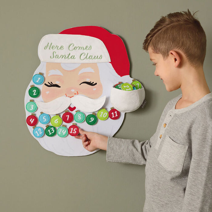 Child interacting with a Santa Claus-themed advent calendar on a plain background