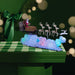 Decorative scene with Santa Claus in a sleigh pulled by skeleton reindeer on a cloud, set against a green checkered tablecloth.