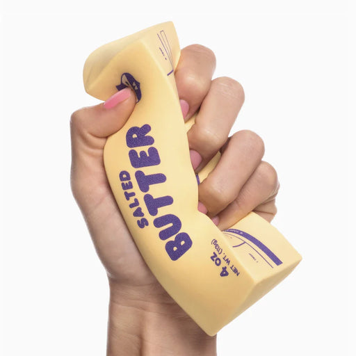 Hand holding a yellow salted butter product with purple text on a white background