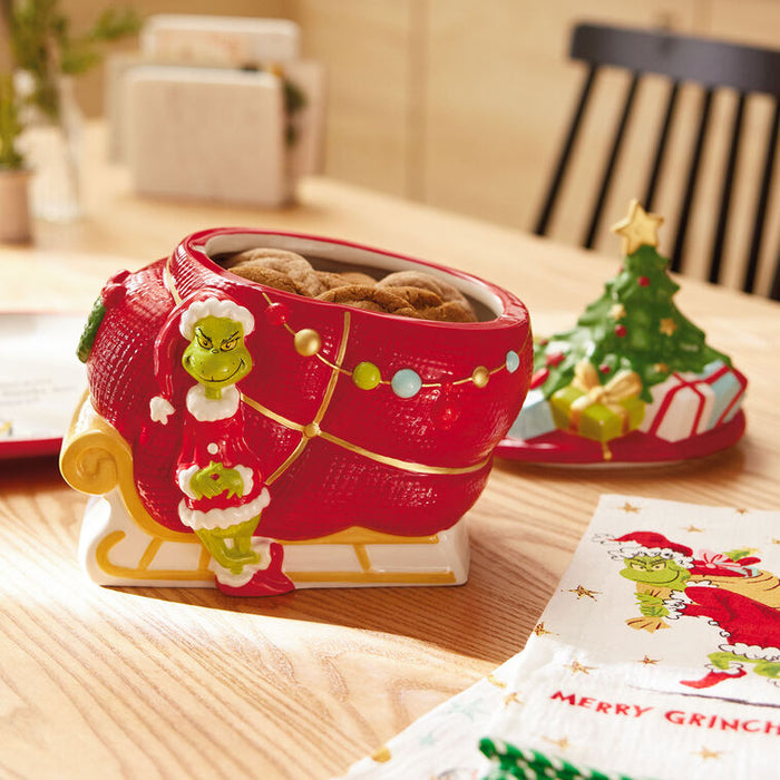 Red sleigh cookie jar with Grinch design on a wooden table