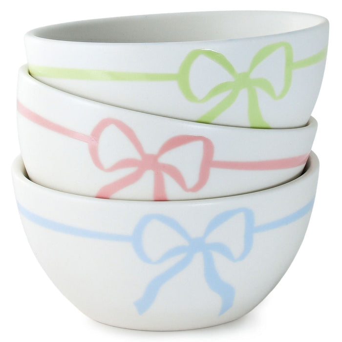 Set of three white bowls with colorful bow designs on a white background
