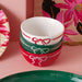 Stack of ceramic bowls with festive designs on a pink surface with floral background