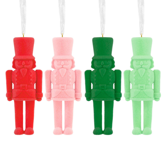 Four nutcracker-shaped candles in red, pink, green, and light green on a white background.