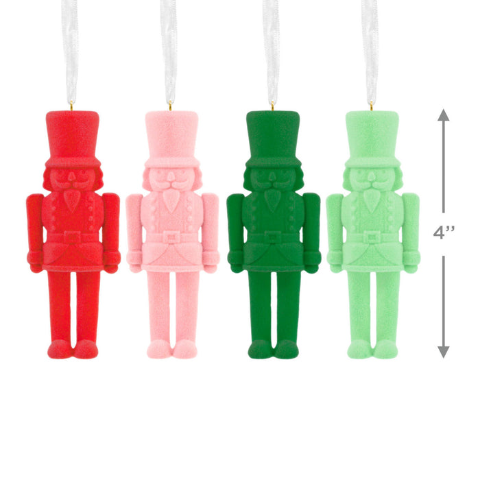 Four nutcracker-shaped candles in red, pink, green, and light green on a white background.