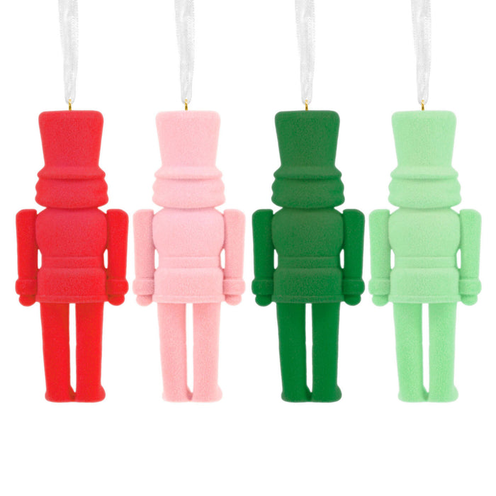 Four colorful toy soldier ornaments in red, pink, green, and light green on a white background.