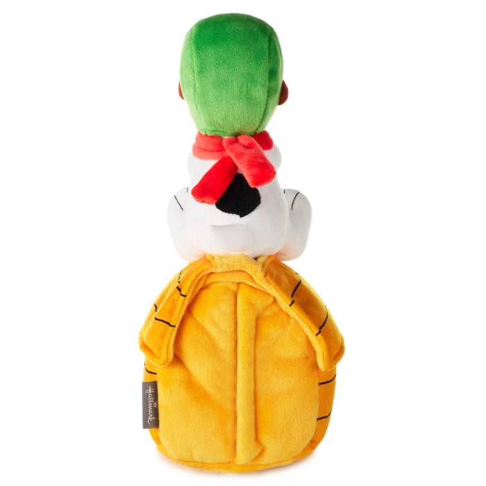 A plush toy backpack shaped like a cartoon turtle character, shown from the back. The backpack features a bright yellow shell, a white body, a green hat, and a red scarf, set against a plain white background.