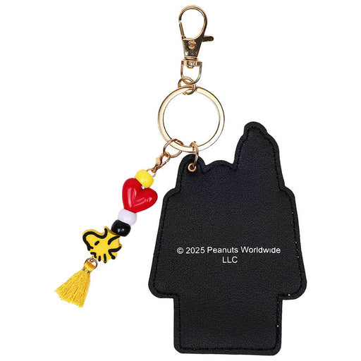 Black Snoopy keychain with colorful charms on a white background