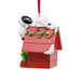 Christmas ornament featuring a doghouse with Snoopy peeking out on a white background