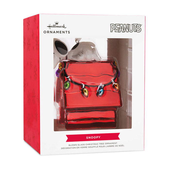 Hallmark Peanuts Snoopy Christmas ornament in its retail box, featuring a red blowen glass tree ornament shaped like Snoopy's house with colorful holiday lights.