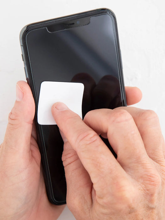 Person applying a white square sticker to a smartphone screen