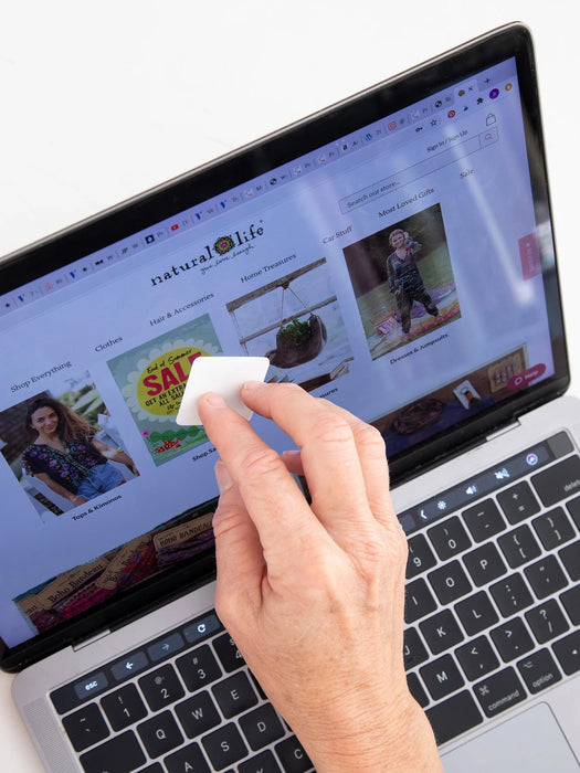 Person using a white remote control in front of a laptop displaying a website.