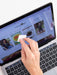 Person using a white remote control in front of a laptop displaying a website.