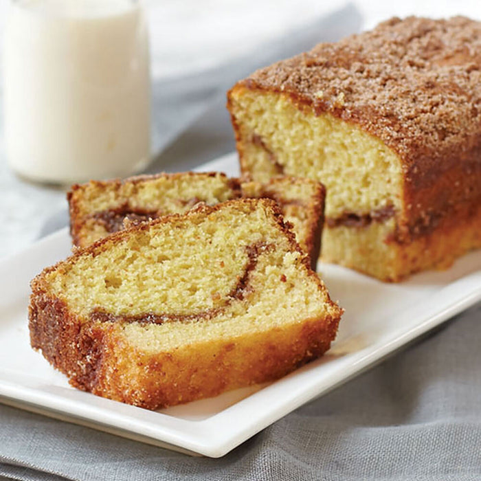 Sliced cinnamon bread on a white plate with a glass of milk in the background.
