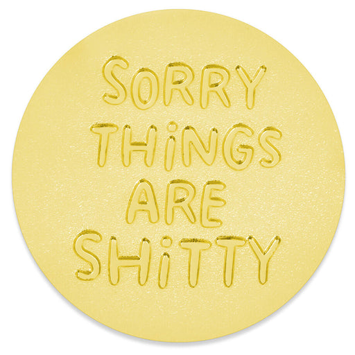 A round, light yellow token featuring the text 'SORRY THINGS ARE SHITTY' embossed in a raised, bubbly font, shown on a clean white background.