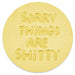 A round, light yellow token featuring the text 'SORRY THINGS ARE SHITTY' embossed in a raised, bubbly font, shown on a clean white background.