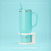 Turquoise mug with straw on a white stand against a light blue background