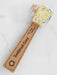 Toothbrush cover with floral design and wooden handle on a white background