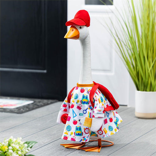 Decorative goose wearing a colorful outfit with a red hat on a wooden floor.