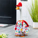 Decorative goose wearing a colorful outfit with a red hat on a wooden floor.