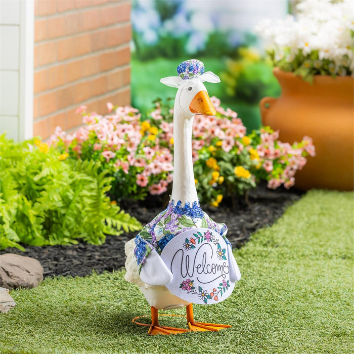 Decorative goose statue with floral design and 'Welcome' text in a garden setting.