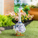 Decorative goose statue with floral design and 'Welcome' text in a garden setting.