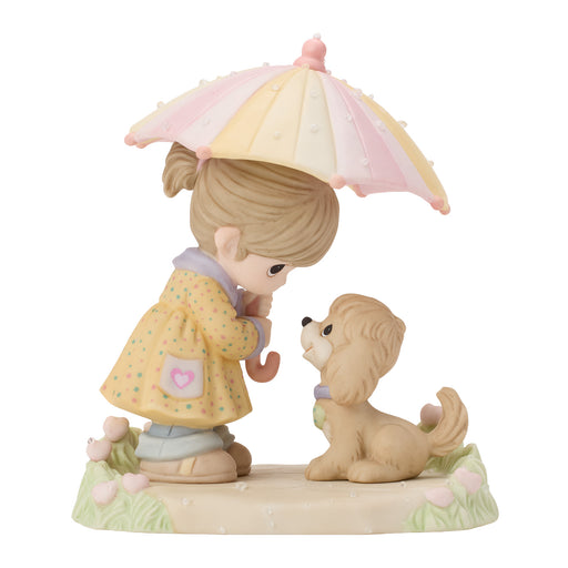 A pastel figurine of a young girl with a pink and cream umbrella, wearing a yellow raincoat and hugging a small tan dog on a decorative base.