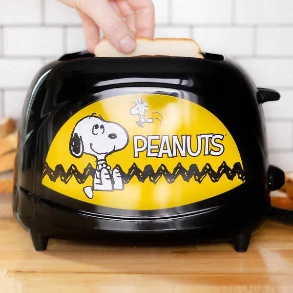 Black toaster with a yellow 'Peanuts' design featuring Snoopy, being used to make toast.
