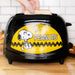 Black toaster with a yellow 'Peanuts' design featuring Snoopy, being used to make toast.