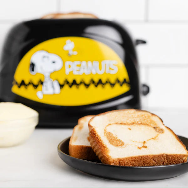 Toaster with Snoopy design and two slices of toast on a plate.