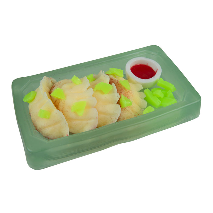 Green toy bento box with sushi and a small bowl of sauce on a white background