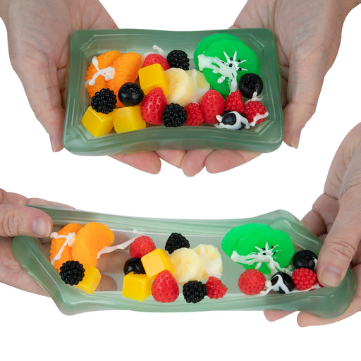 Two green trays with colorful candy train set held by hands against a white background