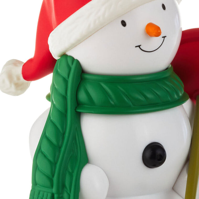 Snowman figurine with a red hat, green scarf, and carrot nose on a white background