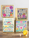 Four colorful greeting cards with floral designs and motivational text on a wooden surface.