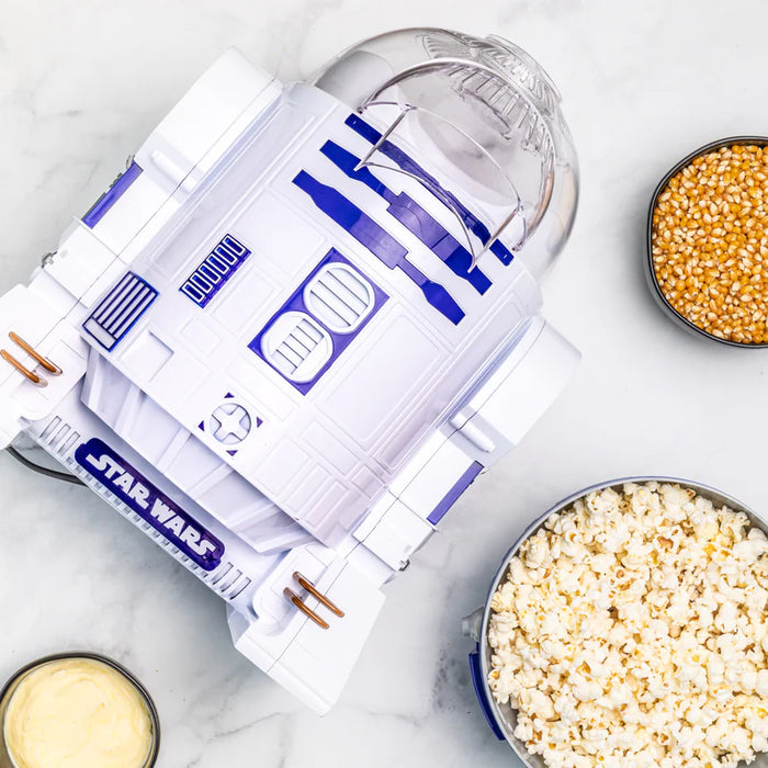 Star Wars R2-D2 popcorn maker with bowls of popcorn and kernels on a marble surface
