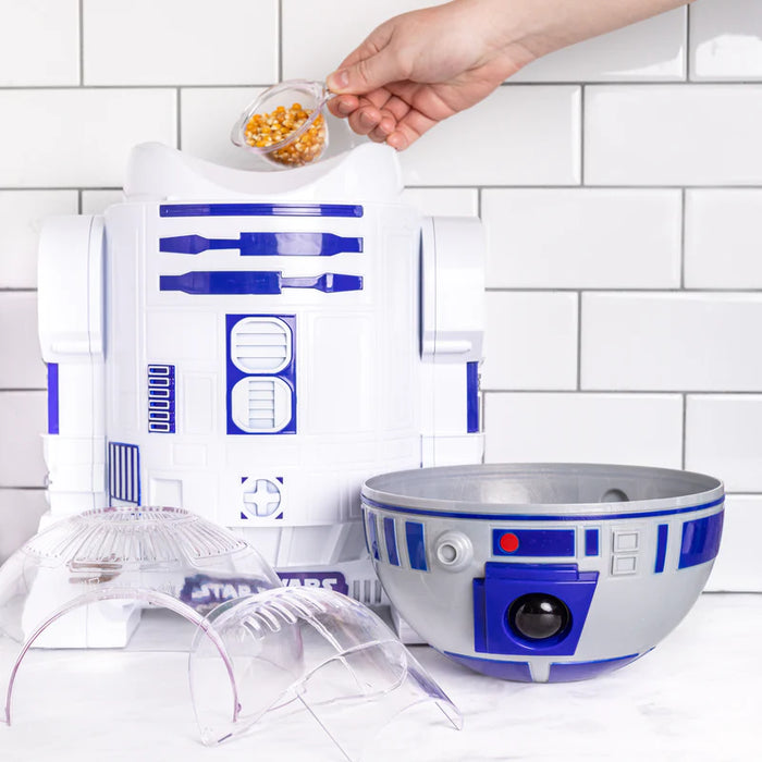 R2-D2-themed popcorn maker and bowl on a kitchen counter with a tiled wall background.