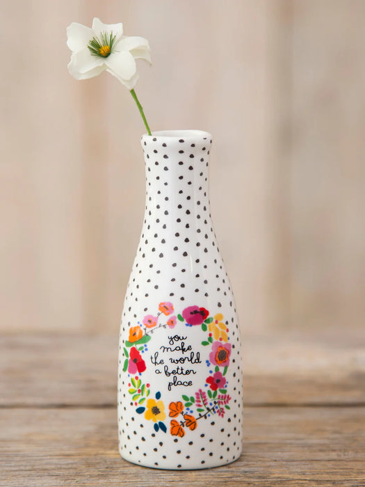 Decorative bottle vase with floral design and text on a wooden surface