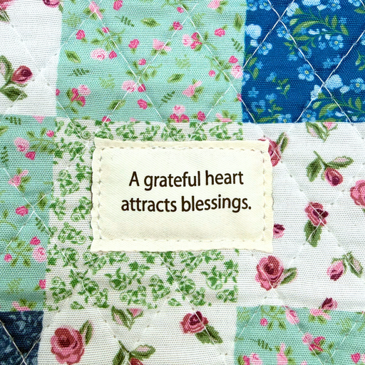 Quilt with floral patterns and a motivational quote on a patch of fabric.