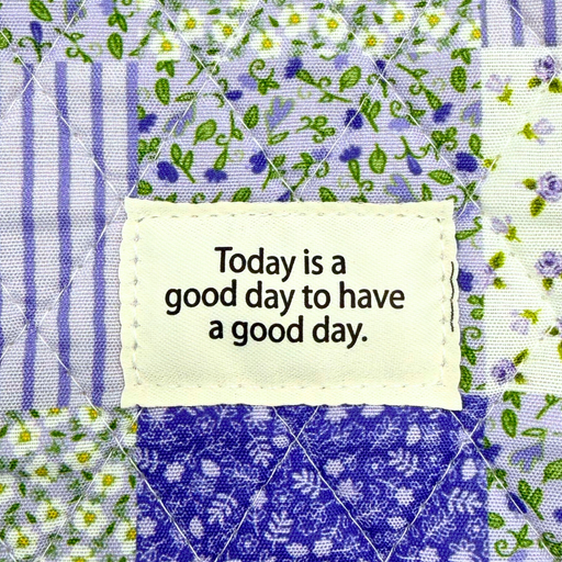 Text 'Today is a good day to have a good day.' on a fabric patch with floral patterns.